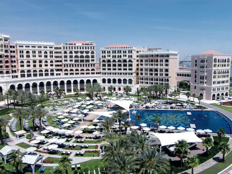 Grande hotel di lusso con piscina, sdraio e giardino curato vicino all'acqua
