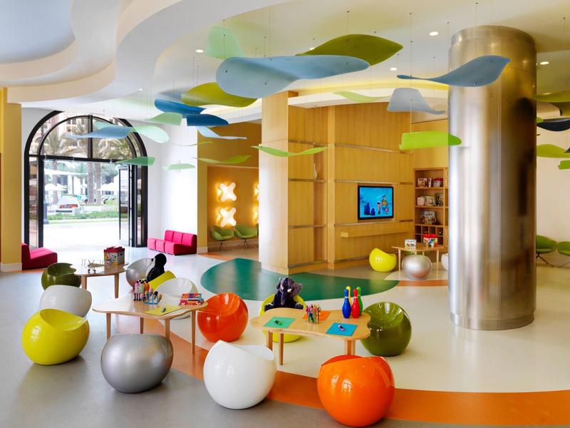 Area giochi colorata e moderna per bambini in un hotel luminoso con sedute dalle forme giocose.