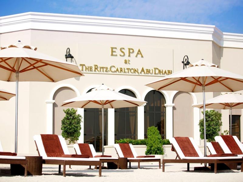 Struttura alberghiera luminosa con lettini e ombrelloni davanti all'ingresso della spa.