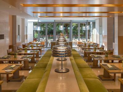 Modern dining area with wooden ceiling and large glass windows overlooking the garden.