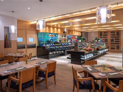 Modern restaurant with wooden furniture and buffet in warmly lit interior.