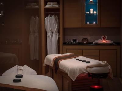 Calm spa room with two massage tables, stone placements, and robes in closet.