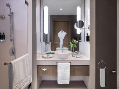 Modern bathroom with sink, mirrors, towels, and shower in a hotel room.