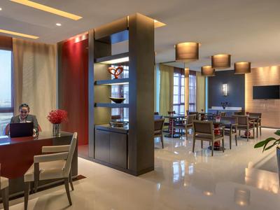 Modern hotel lobby with work and dining areas, elegant design and warm lighting.