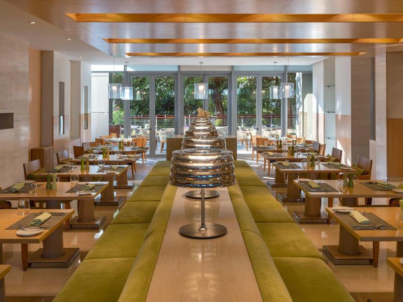 Modern dining area with wooden ceiling and large glass windows overlooking the garden.