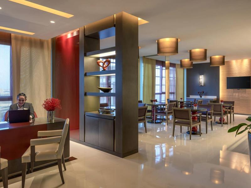 Modern hotel lobby with work and dining areas, elegant design and warm lighting.