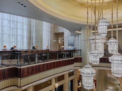 Elegantes Interieur mit großen Fenstern, Holzgeländer und modernem Kronleuchter aus Glas.