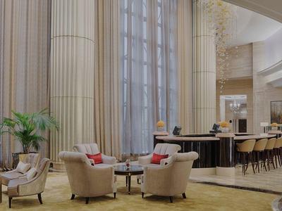 Elegante Hotellobby mit hohen Säulen, großen Fenstern, bequemen Sesseln und Barbereich.