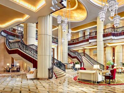 Große Hotellobby mit Marmorboden, eleganten Treppen, Säulen und mehreren Kronleuchtern.