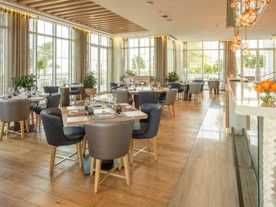 Area ristorante moderna con ampie finestre e pavimento in legno.