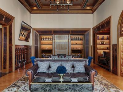 Elegantes Wohnzimmer mit braunem Ledersofa, blauen Akzenten, Holzmöbeln und reich verziertem Deckenlicht.