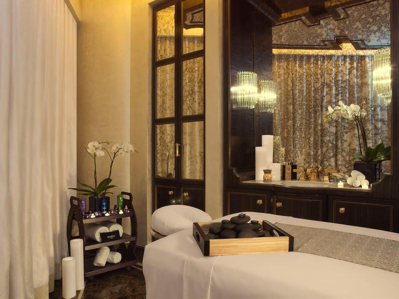 Sala de spa tranquila con camilla de masaje, espejo y iluminación relajante.