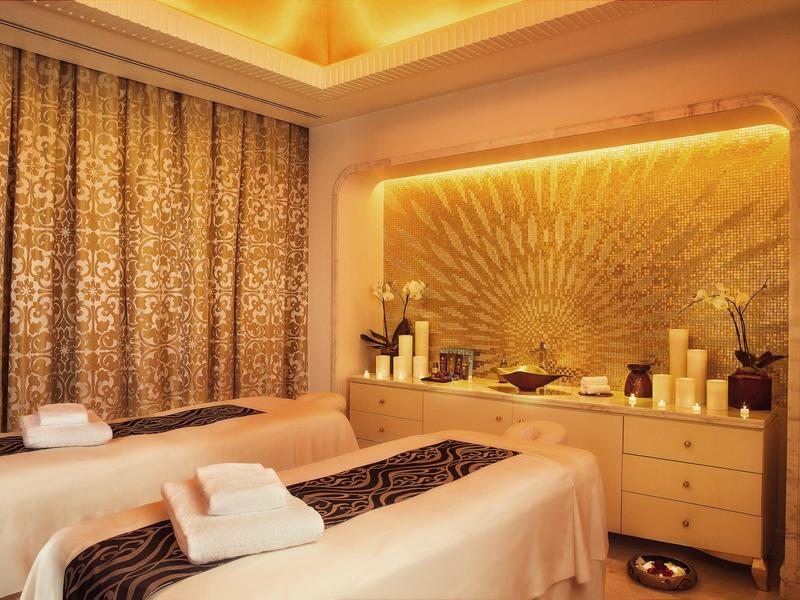 Sala de spa acogedora con dos camillas de masaje, iluminación suave y ambiente relajante.