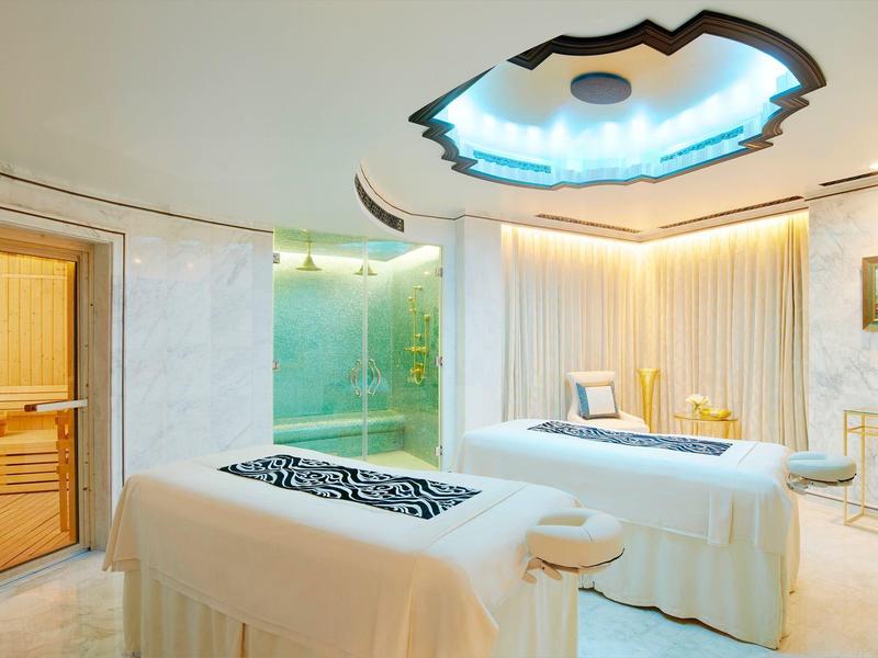 Sala de spa con dos camas de masaje, sauna y iluminación suave para relax.