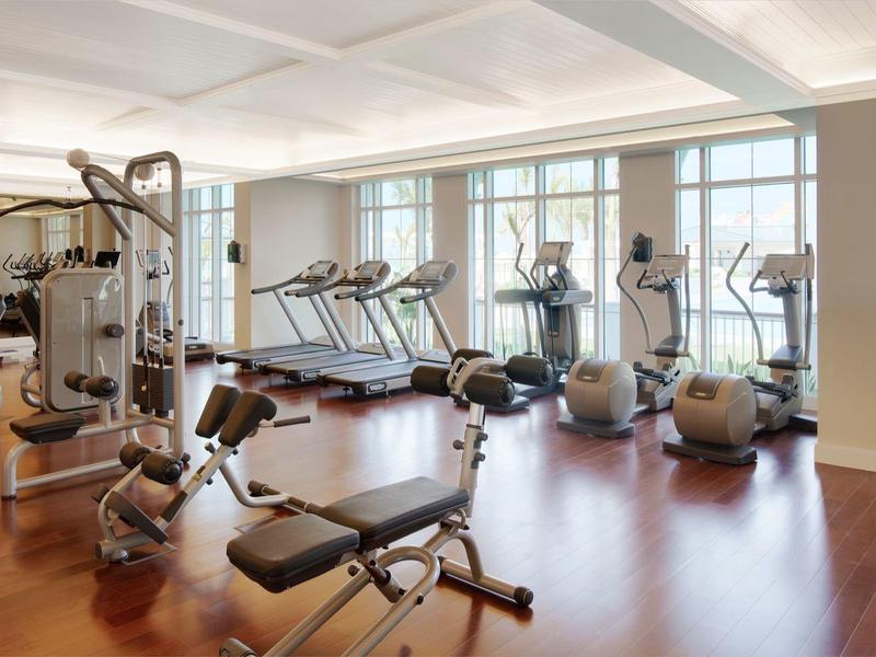 Gimnasio luminoso con equipos modernos y grandes ventanas que permiten la entrada de luz natural.