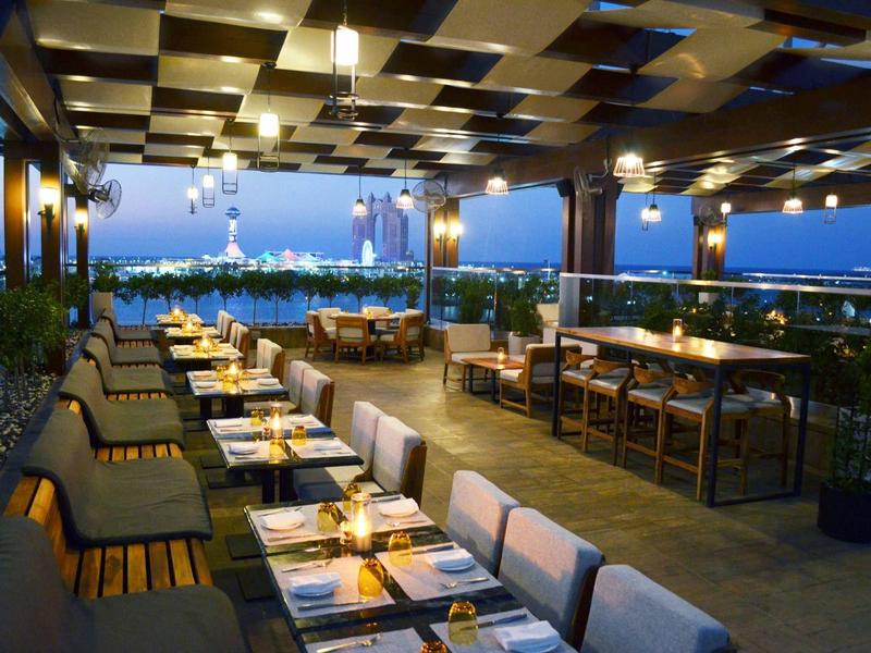 Restaurante elegante con ambiente moderno y vistas a la ciudad al anochecer.