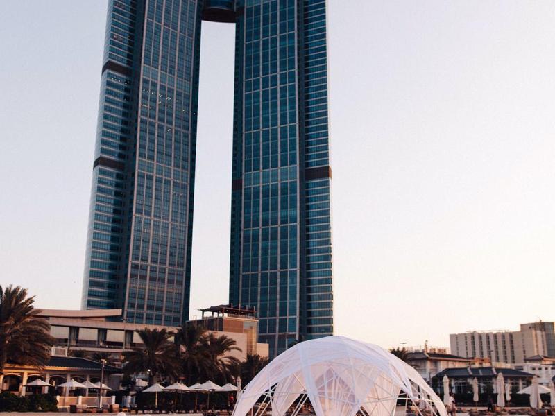 Dos rascacielos conectados con estructura transparente en la playa durante el día.
