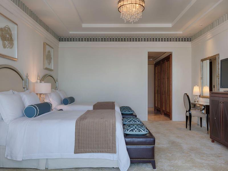 Habitación de hotel elegante con cama doble, banco acolchado, escritorio y armario de madera.