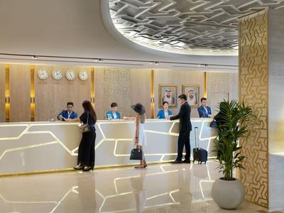 Modern hotel reception with guests and staff in an elegant setting.