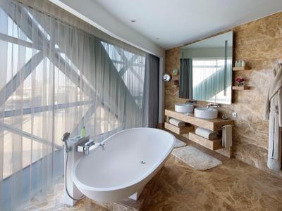 Baño moderno con bañera independiente y grandes ventanas con cortinas.