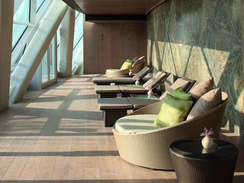 Área de salón bien iluminada con sillones cómodos y cojines verdes en un hotel.