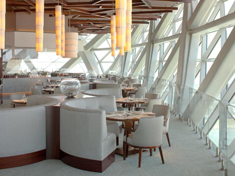 Restaurante moderno con grandes ventanas y áreas de asientos blancos.