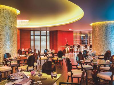 Moderní restaurace s kulatými sloupy, prostřenými stoly a útulným osvětlením.