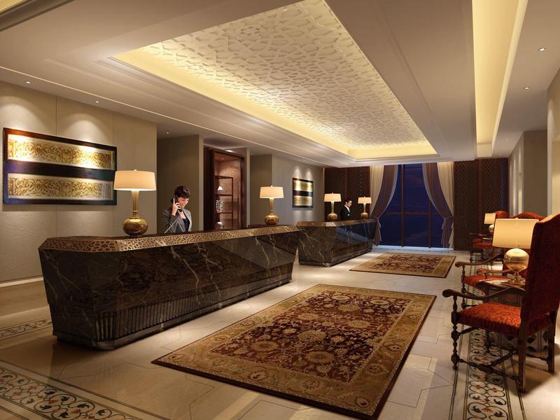 Luxuriöse Hotellobby mit dunklem Tresen, Teppich, Stühlen und warmem Deckenlicht.