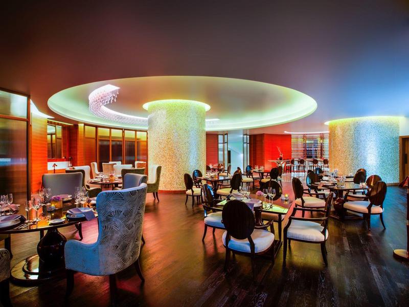 Modernes Restaurant mit runden Säulen, bunten Lichtern und elegant gedeckten Tischen.