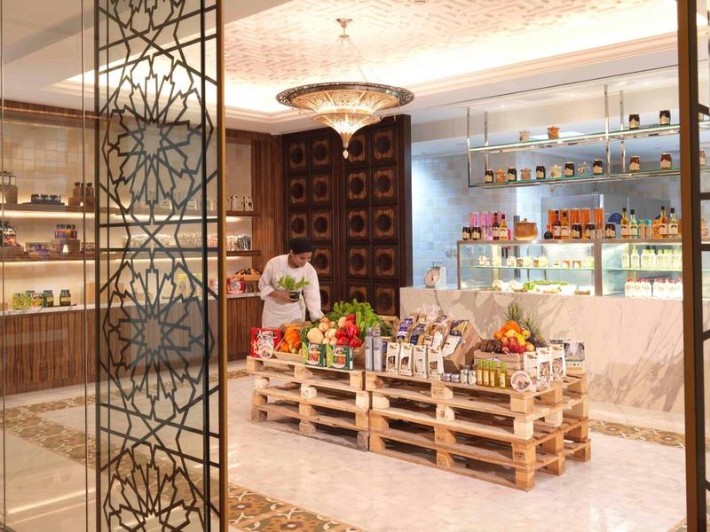 Eleganter Marktstand mit frischem Obst und Gemüse, dekorativ beleuchtet und in Holzpaletten.