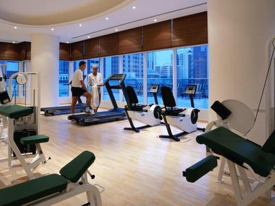 Modern gym with exercise equipment and large windows overlooking the city.