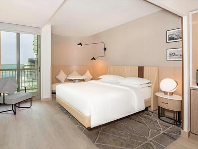 Modern hotel room with double bed, balcony, and sea view.