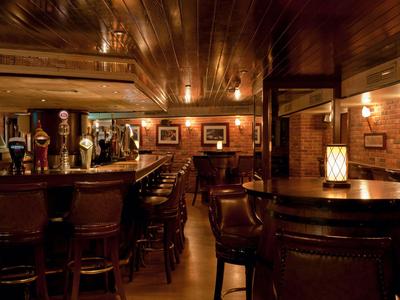 Bar d'hôtel chaleureuse avec boiseries, tabourets en cuir et éclairage tamisé