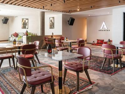 Restaurant d'hôtel moderne avec plafond en bois, tables en marbre et sièges confortables sur des tapis.