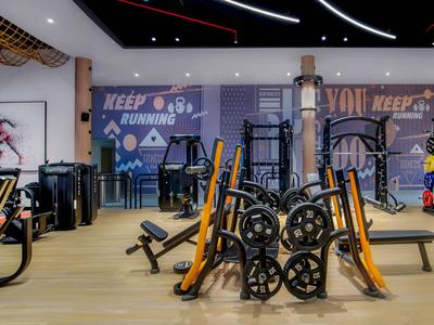 Salle de sport moderne avec divers équipements d'exercice et sols en bois clair.