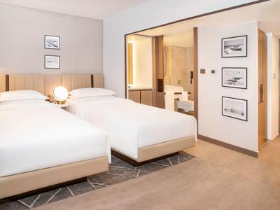 Modern hotel room with two single beds and adjoining bathroom.