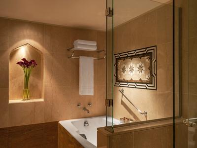 Elegant bathroom with bathtub, glass shower, towels, and flower decor in a niche.