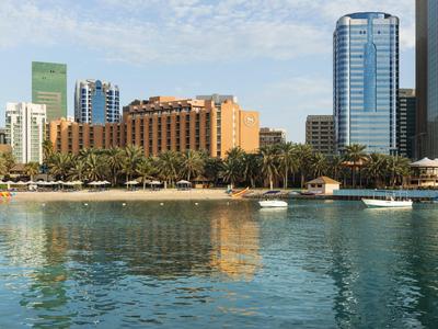 View of a city skyline with hotel buildings and palm trees by the water on a sunny day