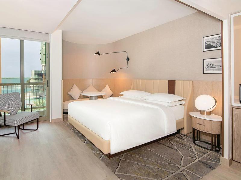 Modern hotel room with double bed, balcony, and sea view.