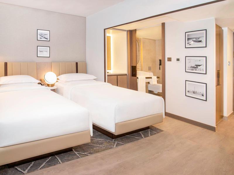 Modern hotel room with two single beds and adjoining bathroom.