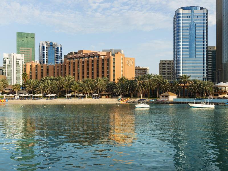 View of a city skyline with hotel buildings and palm trees by the water on a sunny day