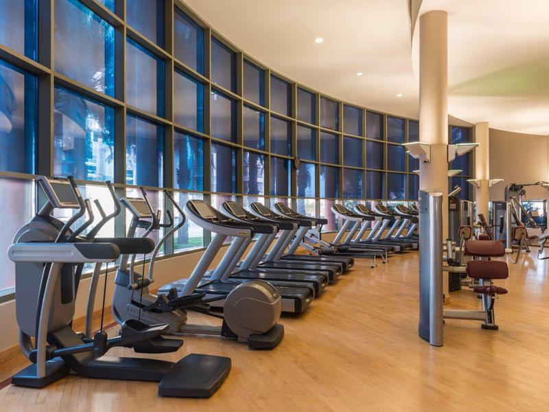 Modern hotel gym with cardio machines and large window wall
