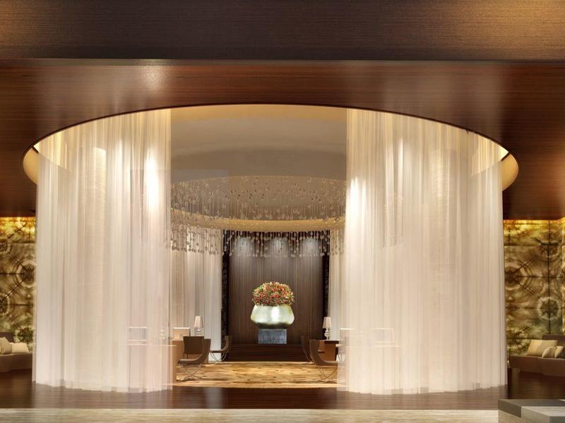 Luxe hotelruimte met elegante ronde gordijn en warm licht.