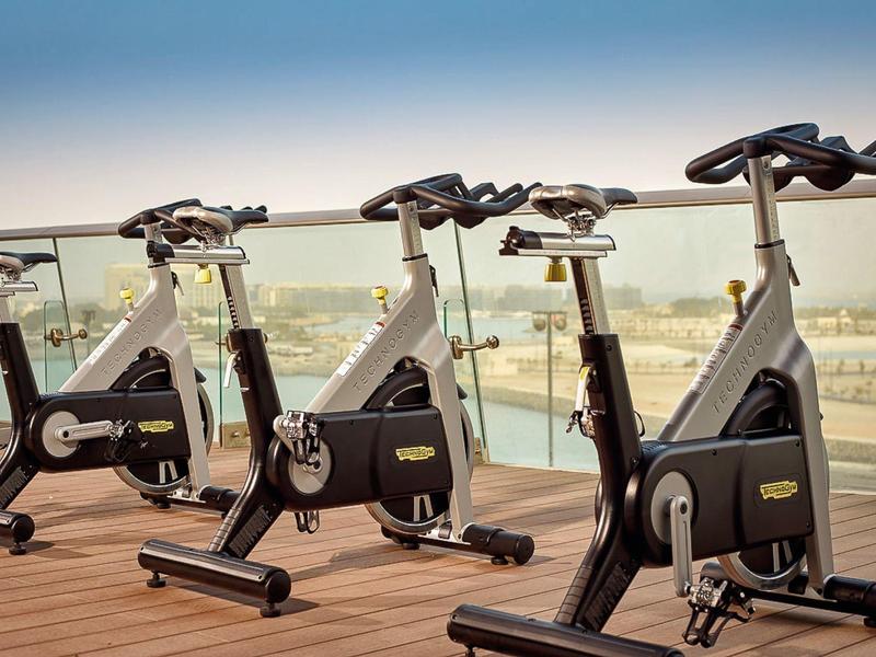 Drie zwarte binnenfietsen op een balkon met glazen balustrade met uitzicht op de stad.