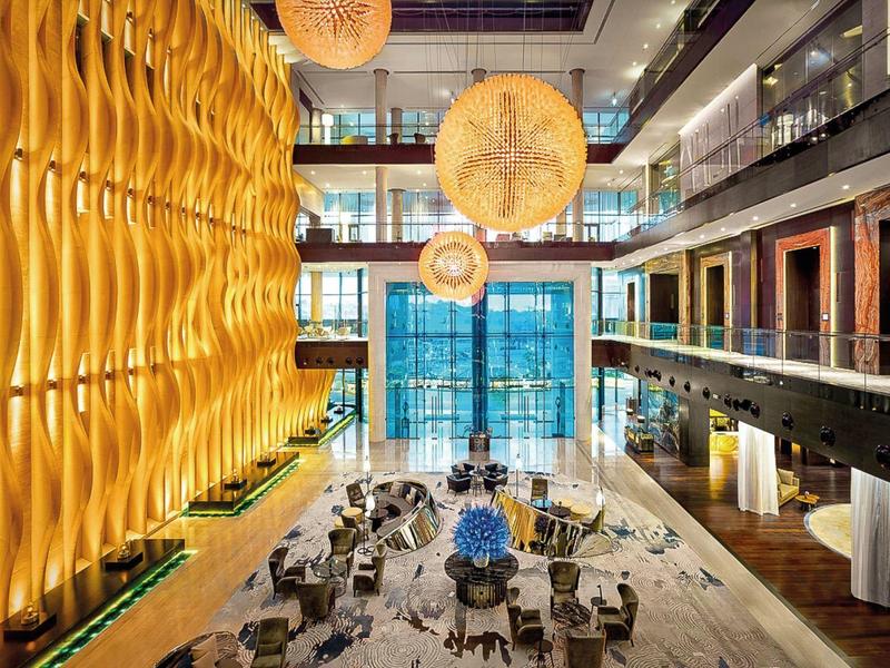 Moderne meerlaagse hotel lobby met elegante houten elementen en opvallende bolvormige verlichting.