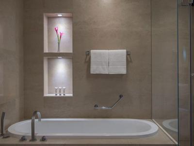 Modernes Badezimmer mit eingebautem Regal, Badewanne und Glastrennwand.