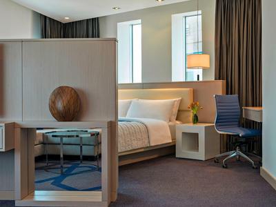 Modernes Hotelzimmer mit Bett, Schreibtisch, Stuhl und einer dekorativen Trennwand.