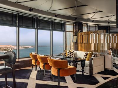 Eleganter Loungebereich mit großen Fenstern, orangefarbenen Sesseln und einem Blick aufs Meer.