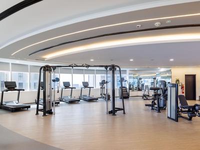 Hell beleuchteter Fitnessraum mit modernen Geräten und Laufbändern in einem Hotel.