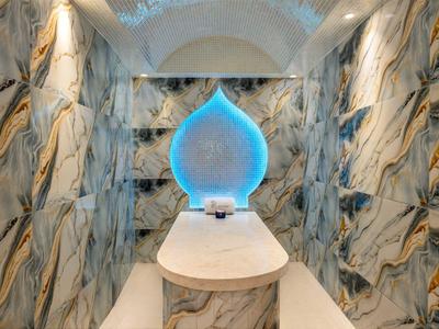 Luxuriöser Raum mit golden gemusterten Marmorwänden und blau leuchtendem Wasserfall-Dekor.